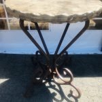 Round travertine table with hammered edge, and decorative wrought iron legs