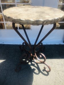 Round travertine table with hammered edge, and decorative wrought iron legs